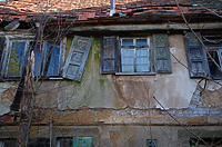 Die Mittelpartie der südlichen Obergeschoss-Außenwand stellt eine verputzte Fachwerkwand über einer massiven Erdgeschosswand dar, in welche Fensterbauteile aus verschiedenen Zeitstellungen eingebaut sind. Das linke Fenster auf dem Bild ist ein dreiflügeliges, großzügiges Fenster, vermutlich aus der 1. Hälfte des 20. Jahrhunderts. Das mittige Fenster mit horizontalen Bleisprossen und Holzkämpfer kann mittels eines, am Boden stehenden Vergleichsexemplars frühestens in die 2. Hälfte des 19. Jahrhunderts einsortiert werden (maschninell hergestellte Beschläge). Das Fenster rechts kann als dreiflügeliges Fenster mit Kämpfer der Jahrhundertwende zugeschrieben werden. Die überlieferten Fensterläden sind im Obergschoss dreigegliederte Rahmenfüllungs-Klappläden aus Holz mit ornamentartigen Ausschnitten und im Erdgeschoss einfache Brettläden. / Haus Osiander in 74549 Wolpertshausen-Rudelsdorf (05.04.2024 - Schäfer, Ferdinand M. (SCHÄFER.PARTNER PartG Architur.Städtebau.Denkmalpflege, Schwäbisch Hall))