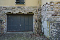 Garagentor ins UG mit unterfangenen Stichbögen dreier früherer Fenster; rechts freiliegende betonierte Umfassungswand. / Landhaus Umkirch/Fulwell Park in 79224 Umkirch (04.2022 - Dipl. Ing. Stefan King, Freiburg.)